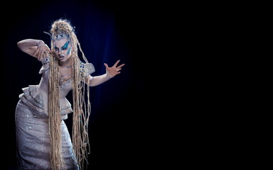 emotional actress woman in makeup and costume queen of elves or snow queen on blue-black background