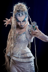 emotional actress woman in makeup and costume queen of elves or snow queen on blue-black background