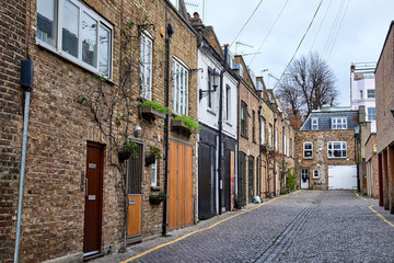 Fototapeta na wymiar Low apartment buildings of bricks in the alley Dunworth Mews leading from Portobello Road in Notting Hill