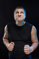 Brutal man actor gesticulates and grimaces on a black background.