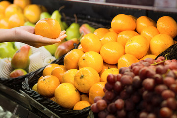 woman's hand choosing orange in supermarket