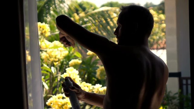 Silhouette of man applying anti-perspirant on armpit standing on terrace, super slow motion 240fps
