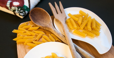 italian pasta and wood kitchen utensils displayed on a chopping board
