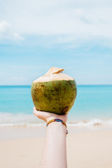 Young woman holding the fresh coconut on Thailand beach