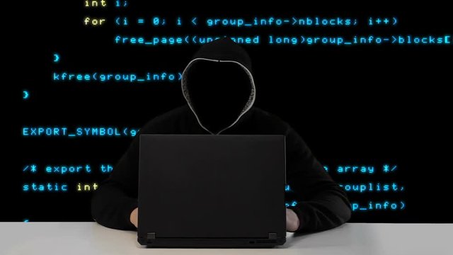 Hacker in black hood with a laptop