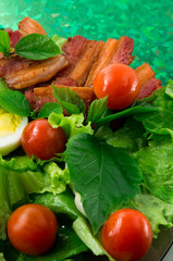 Plate with cherry tomatoes, herbs, olive oil, eggs and bacon