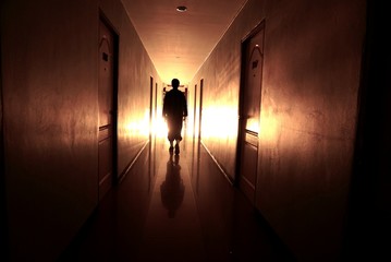 man silhouette walking through a lit corridor, which conveys the concepts of rebirth,evolution and...