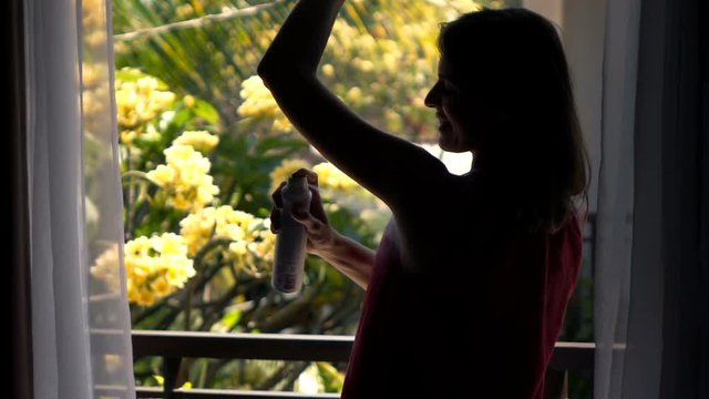 Silhouette of woman applying deodorant on her armpit standing on terrace, super slow motion 240fps
