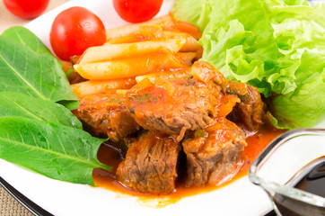 View close-up on a meal of beef stew with penne pasta and herbs