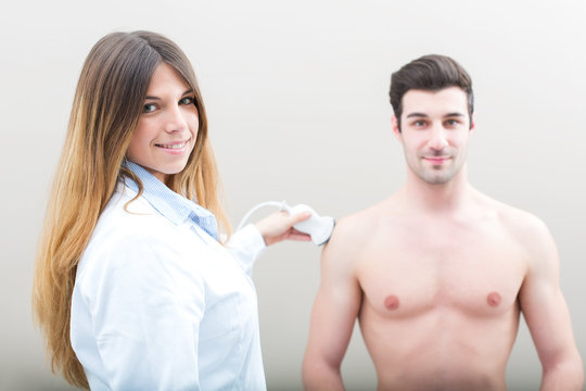 Female doctor visiting her male patient with ultrasound in medical center.
