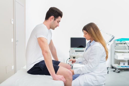 Female doctor visiting her male patient with ultrasound in medical center.