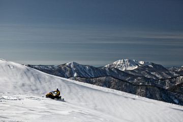 A man on a snowmobile races on snowy slope. State Nature Reserve in Adygea, Russia.