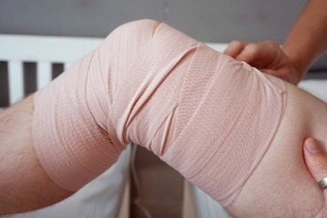 man strapping his painful leg with a bandage