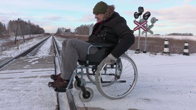 Disabled man on wheelchair near railway crossing