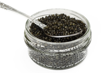 Fototapeta na wymiar Black caviar in a glass jar with spoon closeup isolated on white background