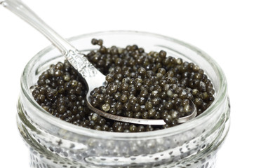 Fototapeta na wymiar Black caviar in a glass jar with spoon closeup isolated on white background