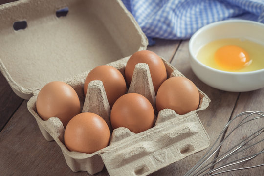 Eggs in carton box and yolk in bowl