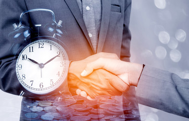 Double exposure of business man handshake with a row of stack money coins and analog clock concept...