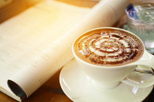 Cup of mocha with newspaper on the table, coffee shop background