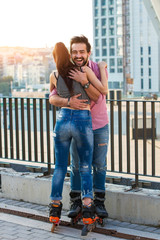 Couple on rollerblades hugging. Laughing man on urban background. The happy laughter.