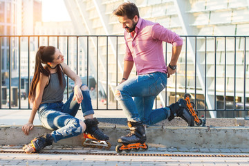 Couple wearing rollerblades. Man kneeling before woman. Find a common hobby.