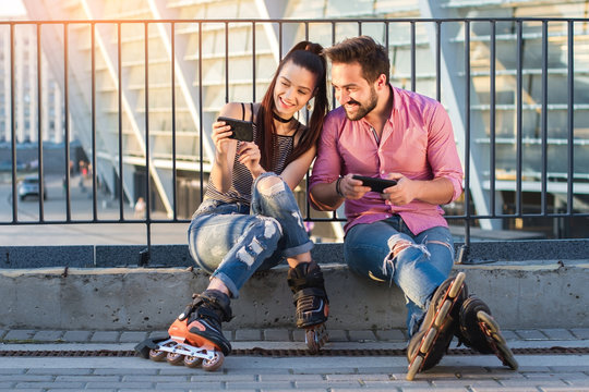 Smiling couple holding cell phones. People on inline skates sitting. Choose the best photo.