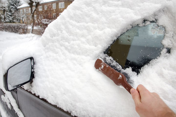 Man cleans the car from snow wih brush