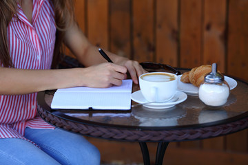 Women's hands writting in diary with coffee