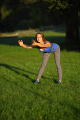 Young woman doing forward bend on grass