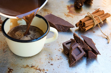 Hot chocolate poured from pot into mug cup. Winter times drink concept. Delicious cold weather beverage.