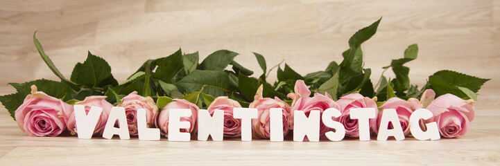 rosa Rosen auf einem Holzhintergrund mit Text Valentinstag