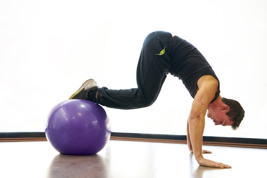 Athletic man exercising with ball in gym
