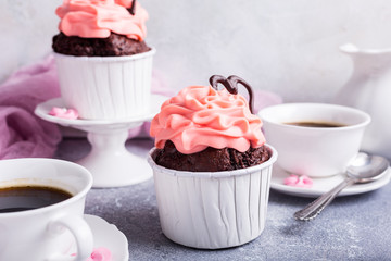 Valentines and Mother Day, wedding greeting card with beautiful chocolate cupcake, pink cream and heart on gray stone background.
