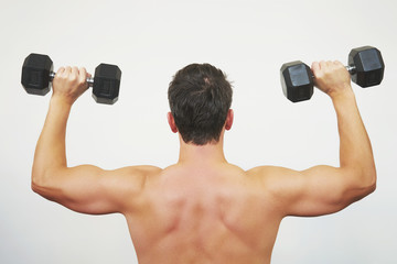 Fototapeta na wymiar Fit muscular man exercising with dumbbell