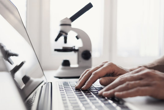 Scientist Or Student Using  Laptop Computer And Microscope