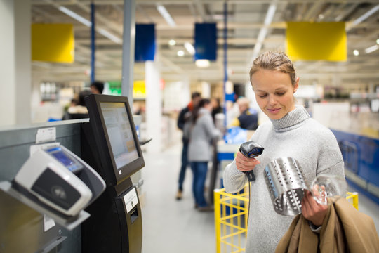 Pretty, young woman using self service checkout in a store