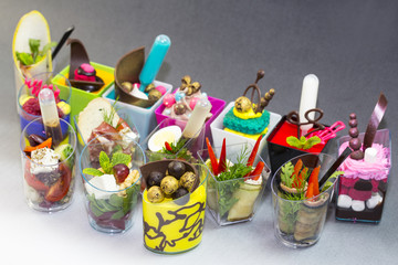 Mini desserts and meat canapes vegetable snacks in plastic cups canapes