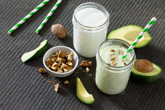 Healthy green cocktail with avocado and walnuts in a bank of gla
