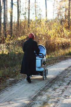 Grandmother walking in autumn forest with little granddoughter. Back view, not recognisable.
