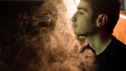 Young handsome guy smoking hookah alone closeup