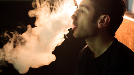 Young handsome guy smoking hookah alone closeup