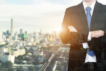 Double exposure businessman standing with his arms crossed again city