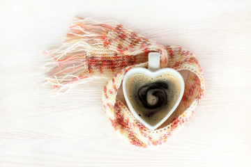 warming power of love/ pink scarf wrapped around the mug with coffee top view 