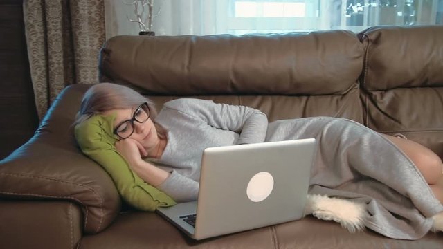 Young woman using her laptop feeling sleepy