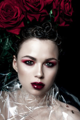 Beauty Fashion Model Woman face. Portrait with Red Rose flowers. Red Lips and Nails. Beautiful Brunette Woman with Luxury Makeup, perfect skin. Valentine.