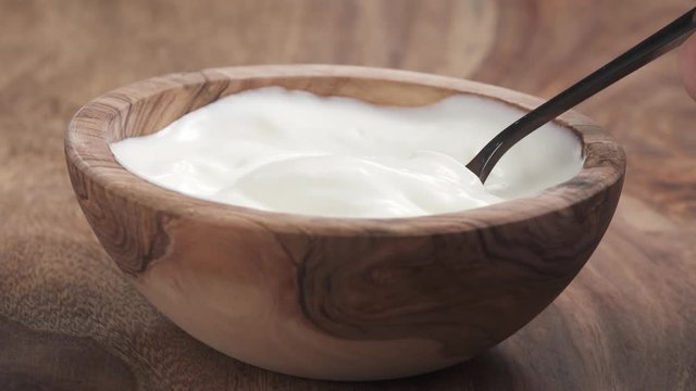 eating with spoon yougurt cream from wooden bowl on table in slow motion, 180fps prores footage