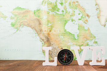 Love to travel. Magnetic compass and blurred world map as background. Place for text.