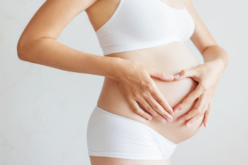 Pregnant woman in white underwear. Young woman expecting a baby