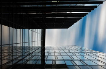 Glass modern business building. Looking up on the reflection and the moving clouds.