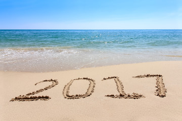 Year 2017 written at the sand beach with sea wave water